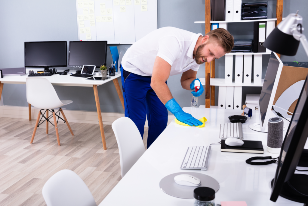 Jeune homme avec gants de ménage nettoie un bureau